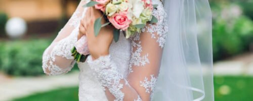 Young happy beautiful  bride in white  elegant wedding dress with bouquet posing outdoor  in park. Fashion image of pretty  bridal woman.